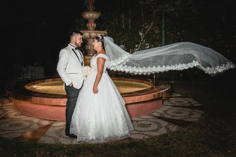 El velo de la novia vuela de noche junto a una pileta
