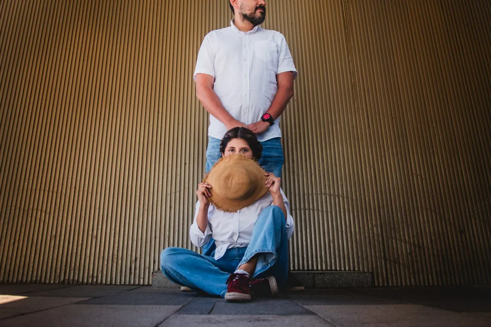 Marco de pie y Sayda sentada en el suelo, tapándose la cara con el sombrero