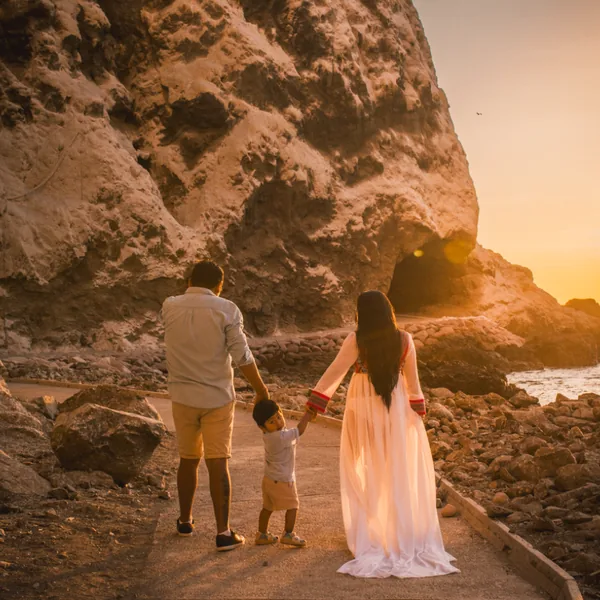 Una familia camina de la mano junto al mar al atardecer