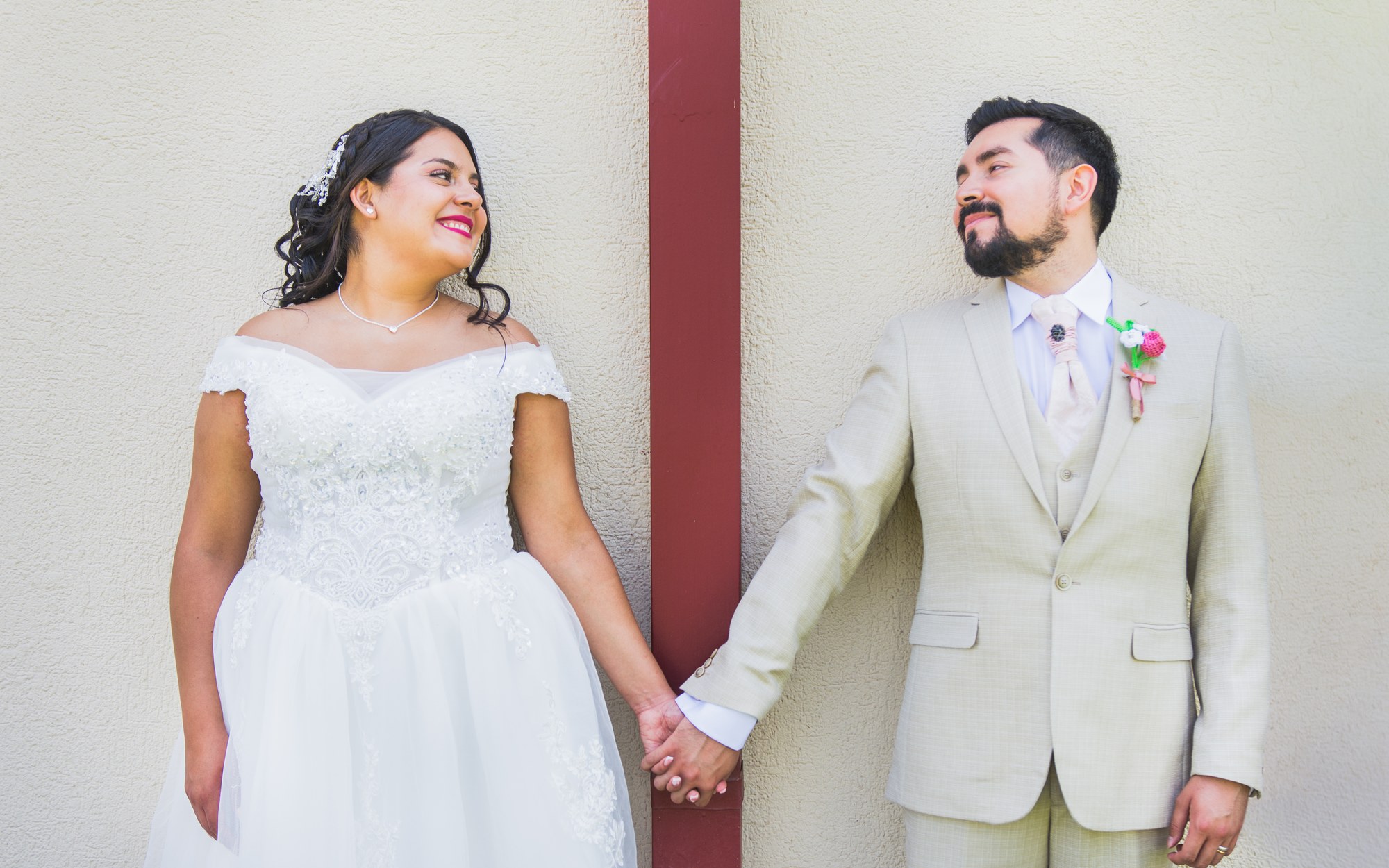 Couple holding hands, leaning against a wall